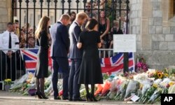 Prens William (dezyèm a goch) Kate, Prensès de Gal, epi Prens Harry ak Meghan, Duchès Sussex la gade bouke flè moun kite pou defen Rèn Elizabeth II devan Chato Windsor la, Samdi 10 Sept. 2022.