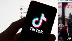 The TikTok logo is seen on a mobile phone in front of a computer screen which displays the TikTok home screen, March 18, 2023, in Boston. 