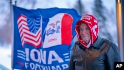 FILE - A man stands next to a flag that reading "Iowa for Trump" in Urbandale, Iowa, Jan. 11, 2024. Voters in the state are participating in caucuses on Jan. 15, 2024, that launch the Republican presidential nomination process.