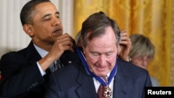 Tổng thống Mỹ Barack Obama đeo Huân chương Tự do cho cựu Tổng thống George H.W. Bush trong một buổi lễ tại NHà Trắng ở Washington, ngày 15 tháng 2, 2011.