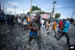 Foto: Yon manifestan pote yon baton bwa pandan yon manifestasyon pou mande Premye Minis Ariel Henry bay demisyon li nan Petion-Ville, Ayiti, 3 Oktob, 2022.