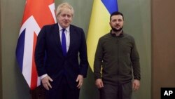 Nan foto sa a ke Biwo de Pres Prezidansyel Ikrenyen bay jounalis yo, Premye Minis Britanik la Boris Johnson (a goch) ak Prezidan Ikrenyen an Volodymyr Zelenskyy poze pou yon foto nan vil Kyev, kapital Ikren, Samdi 9 Avril 2022. 