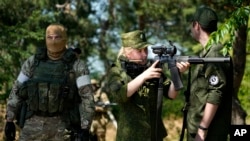 A Russian Army soldier looks through a sniper rifle scope as she and other soldiers guard a group of foreign journalists visiting a captured Ukrainian checkpoint and well-fortified trenches near Schastia town, on the territory which is under the Governmen