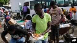 Foto Achiv: Yon mesye vann manje cho nan yon mache nan Potoprens, Ayiti. 