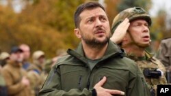 Tổng thống Ukraine Volodymyr Zelenskyy và binh sĩ hát quốc ca, chào cờ khi thăm thành phố Izium, vùng Kharkiv, Ukraine, 14/9/2022. 