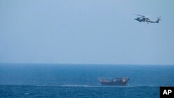 FILE - A U.S. Navy Seahawk helicopter flies over a stateless dhow later found to be carrying a hidden arms shipment in the Arabian Sea, May 6, 2021. 