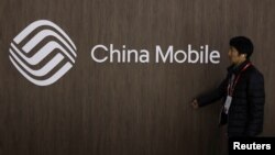 Một người đàn ông đi ngang qua logo của hãng China Mobile. 