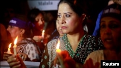 Women hold lighted candles during a rally