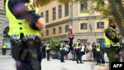 Polisler, İsveç'in Stockholm kentindeki Mynttorget Meydanı'nda aralarında Irak bayrağı tutan bir protestocunun bulunduğu göstericilerin yanında duruyor.