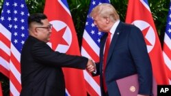 Tư liệu - Ảnh chụp ngay 12/6/2018, Chủ tịch Triều Tiên Kim Jong Un, trái, và TT Mỹ Donald Trump bắt tay vào lúc kết thúc cuộc gặp tại trung tâm du lịch Capella trên đảo Sentosa, Singapore.