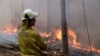 A firefighter keeps an eye on a controlled fire as they work at building a containment line at a wildfire near Bodalla, Australia, Sunday, Jan. 12, 2020.