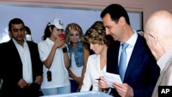 Tổng thống Syria Bashar al-Assad (thứ hai từ phải sang) cùng phu nhân đi bầu tại một điểm bỏ phiếu ở Damascus, 3/6/2014. 