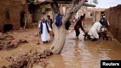 ہرات میں حالیہ سیلاب سے ہونے والی تباہی کا ایک منظر۔ دیہاتی پانی میں ڈوبے اپنے مکانات سے سامان نکال رہے ہیں۔