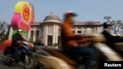 Motorists ride past the State Bank of Vietnam's building in Hanoi December 23, 2014. Vietnam's credit growth is projected to pick up in 2015 to between 13-15 percent to accommodate faster economic growth, compared with 13 percent this year, the central ba