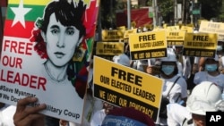 Anti-coup protesters hold signs as they gather in Mandalay, Myanmar, Friday, Mar. 5, 2021. 