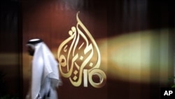 A Qatari employee of Al Jazeera Arabic language TV news channel passes by the logo of Al Jazeera in Doha, Qatar, Wednesday Nov. 1, 2006. The English language offshoot of Qatar based pan-Arab television news channel Al Jazeera said on Tuesday it will sta