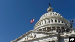 FILE - an American flag flies over Capitol Hill in Washington. 