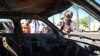 First responders check a charred car near a building hit by a rocket fired from Lebanon in Kiryat Ata in Israel's Haifa district on October 19, 2024, amid the ongoing war between Israel and Hezbollah.