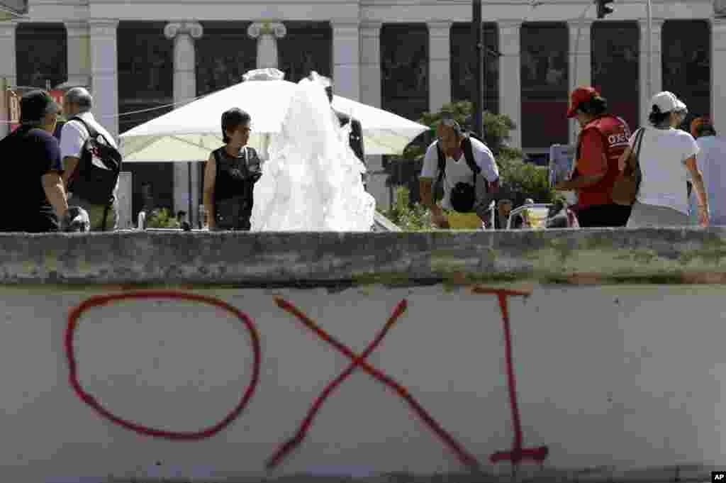 Commuters exit from a metro station as a graffiti reading ''No'' referring to the upcoming referendum in Athens, June 29, 2015. 