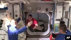 Phi hành gia Kate Rubins ở trạm ISS (áo xanh) chào đón phi hành gia Mike Hopkins (áo đỏ) từ tàu SpaceX Dragon, ngày 17/11/2020.