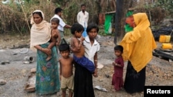 Người dân đứng cạnh tàn tích của một khu chợ đã bị đốt cháy, ở làng Rohingya, bang Rakhine, Myanmar, 27/10/2016.