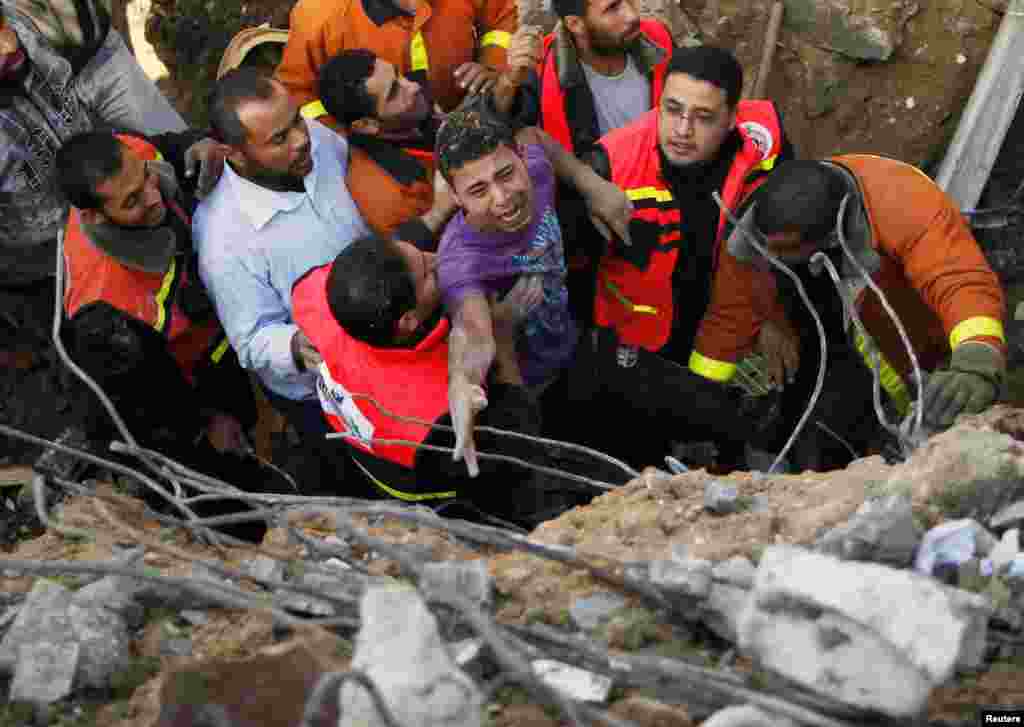  C&aacute;c th&agrave;nh vi&ecirc;n Quốc ph&ograve;ng D&acirc;n sự Palestine gi&uacute;p người sống s&oacute;t sau khi &ocirc;ng được l&ocirc;i ra từ dưới đống đổ n&aacute;t của ng&ocirc;i nh&agrave; bị ph&aacute; hủy sau cuộc kh&ocirc;ng k&iacute;ch của Israel v&agrave;o th&agrave;nh phố Gaza, ng&agrave;y 18/11/2012. 