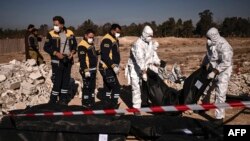 Các thành viên của lực lượng phòng vệ dân sự White Helmets của Syria vận chuyển các túi đựng thi thể chứa hài cốt người được tìm thấy từ một ngôi mộ tập thể ở Damascus, ngày 16 tháng 12 năm 2024.