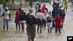 Cư dân rời bỏ nhà cửa bị ngập lụt trong một khu vực ở Port-au-Prince, Haiti, ngày 25/8/2012