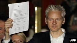 Ông Assange giơ cao hồ sơ của tòa án cho các nhà báo thấy, bên ngoài một Tòa án ở London, sau khi ông được phép tại ngoại