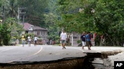 Residents walk on a damaged highway at Loboc township, Bohol province in central Philippines, Oct. 16, 2013.