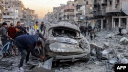 A man inspects a destroyed vehicle amidst debris and rubble at the site of Israeli bombardment on a residential block in Jalaa Street in Gaza City on January 14, 2025 amid the ongoing war in the Palestinian territory between Israel and Hamas.