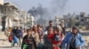 TOPSHOT - Palestinians displaced from shelters in Beit Hanoun cross the main Salaheddine road into Jabalia in the northern Gaza Strip following Israeli army evacuation orders on November 12, 2024, amid the ongoing war in the Palestinian territory between 