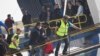 Officers from the European Union’s border protection agency, Frontex, lead a migrant as they get in a ferry in the port of Mytilini, Lesbos island , Greece, April 8, 2016. 