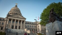 (FILES) People stand next to the Confederate Mothers statue (R) outside the Mississippi State Capitol building during the state legislature's historic vote to change the Mississippi flag in Jackson, Mississippi on June 28, 2020.