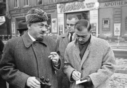 John Steinbeck tại chốt kiểm soát quân sự từ phía Tây Berlin, 11 tháng 12, 1963. Có một khoảnh khắc, Steinbeck chống lại một lính gác ở phía Đông và bước qua lằn sơn trắng phân cách biên giới Đông và Tây Đức. Ông thăm Berlin 5 ngày trong chuyến thăm Châu Âu 2 tháng, kết thúc bằng chuyến thăm Moscow. (AP Photo/Edwin Reichert)