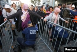 Cư dân Molenbeek, ngoại ô Brussels, được cảnh sát rà soát trước khi tham gia buổi lễ tưởng niệm nạn nhân của các cuộc tấn công chết người ở Paris, ngày 18/11/2015.