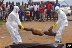 Các nhân viên y tế đặt thi thể của một người mà họ nghi là chết vì nhiễm virus Ebola vào một chiếc túi đựng.