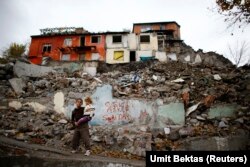 Cậu bé tị nạn người Syria bế em gái trở về nhà ở huyện Hacibayram ở Ankara, Thổ Nhĩ Kỳ. Những tác động kinh tế-xã hội của vụ khủng hoảng người tị nạn đã hiện rõ qua sự tăng vọt của tội phạm và những vấn nạn xã hội khác.