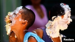 Children react with their faces covered in cream from a 450-metre long cake that was prepared as part of celebrations to mark the 450th anniversary of the city of Rio de Janeiro March 1, 2015. REUTERS/Ricardo Moraes (BRAZIL - Tags: SOCIETY ANNIVERSARY FOO