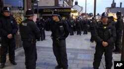 Police officers form a cordon around a group of local people on Eltham High Street in London, Wednesday, Aug. 10, 2011. A large group of local men gathered in the area on Wednesday to deter looters and a large number of police officers was also present to