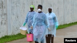 Nhân viên y tế xách các thùng chứa chất khử trùng tại một trung tâm điều trị Ebola tại Monrovia, Liberia.