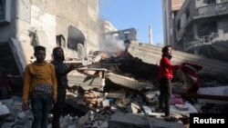 Palestinians inspect a house destroyed in an Israeli strike, in Khan Younis