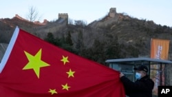 A visitor holds the Chinese flag near the Badaling section of the Great Wall of China on the outskirts of Beijing on Feb. 8, 2022.