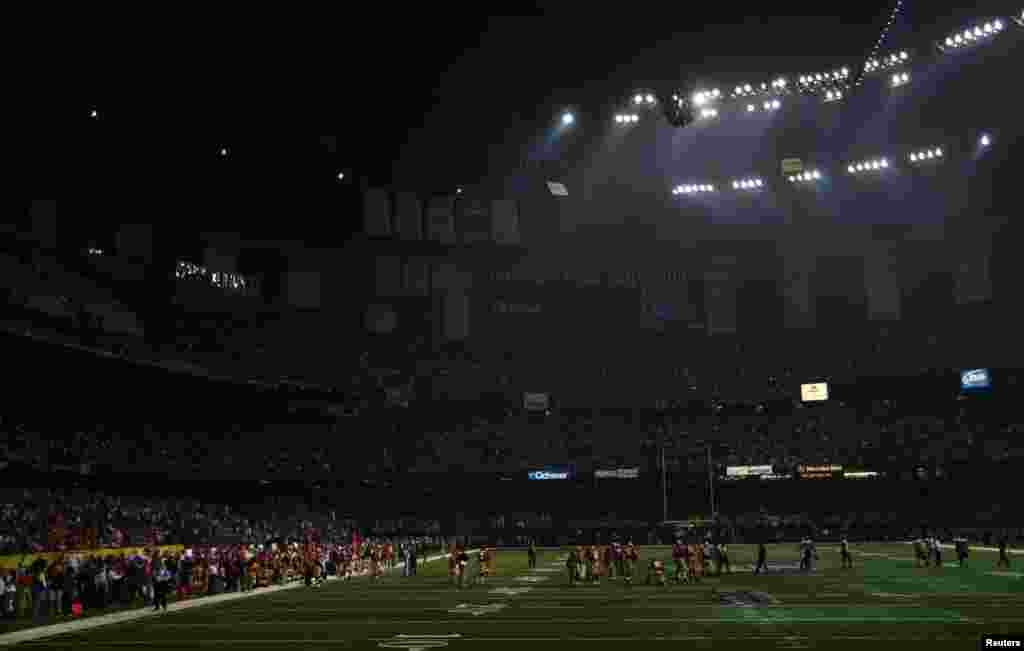 Players mill around the field after half of the lights went out during the third quarter of the NFL Super Bowl XLVII football game between the Baltimore Ravens and the San Francisco 49ers in New Orleans, Louisiana, February 3, 2013.