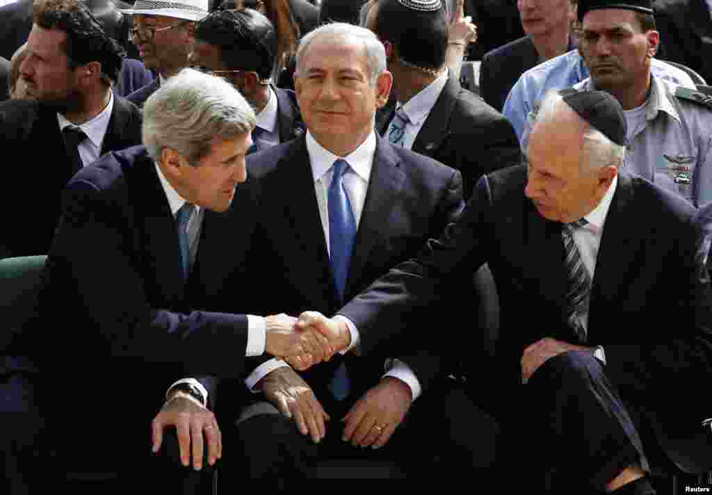 Tổng thống Israel, Shimon Peres, với tay ngang qua Thủ tướng Israel, Benjamin Netanyahu, để bắt tay Ngoại trưởng Mỹ Kerry tại lễ tưởng niêm nạn nhân Holocaust hằng năm tại Jerusalem, 8/4/2013.