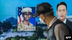 In this photo taken in Seoul on August 16, 2023, a man walks past a television showing a news broadcast featuring a photo of US soldier Travis King (C), who ran across the border into North Korea while part of a tour group visiting the Demilitarized Zone 