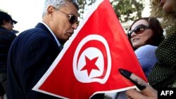 Một người phụ nữ Tunisia cầm lá cờ với ngón tay dính mực sau khi đi bỏ phiếu ở Tunis, 23/10/2011