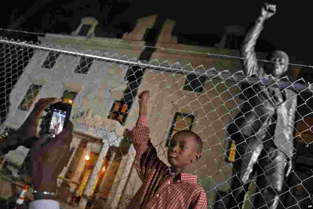 Keaton Anderson, 10, poses for a photograph for his father Dijon Anderson as they visit the statue of Nelson Mandela at the South African Embassy in Washington, Dec. 5, 2013. 