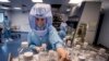 FILE - In this March 27, 2021 file photo a laboratory worker simulates the workflow in a cleanroom of the BioNTech Corona vaccine production in Marburg, Germany, during a media day. 